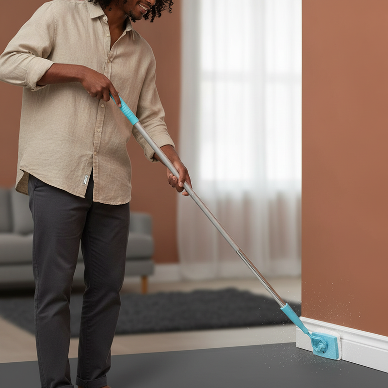 A person uses the Baseboard Buddy mop to clean a baseboard in a room corner, showing its extended reach.